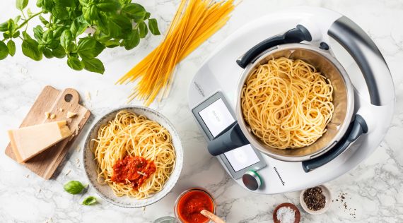 Blick von oben auf den Thermomix® mit Spaghetti im Topf, daneben ein Teller mit Spaghetti und Tomatensoße – Foto: Anna Gieseler