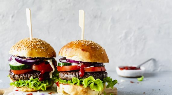 Zwei Burger mit Rindfleischpatties, Salat und Tomate auf einem hellen Untergrund – Foto: Désirée Peikert