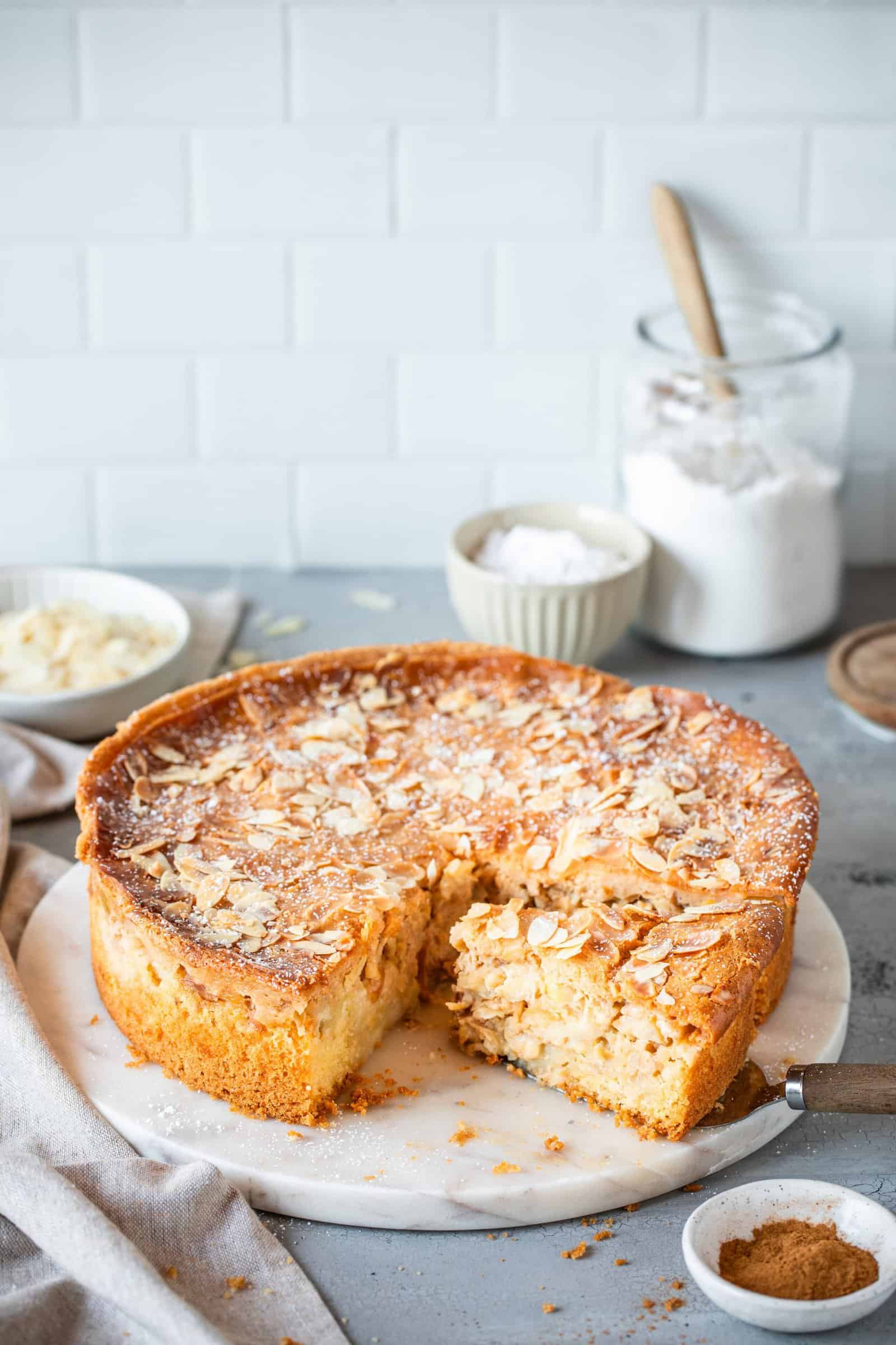 Apfelkuchen mit Mandelblättchen, angeschnitten auf hellem Teller