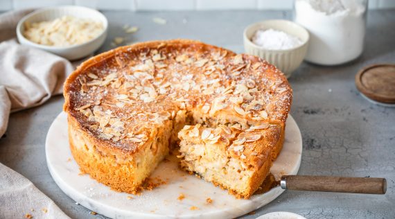 Apfelkuchen mit Mandelblättchen, angeschnitten auf hellem Teller